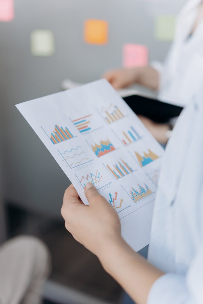 Close-up of hands holding paper with various business graphs in an office setting.